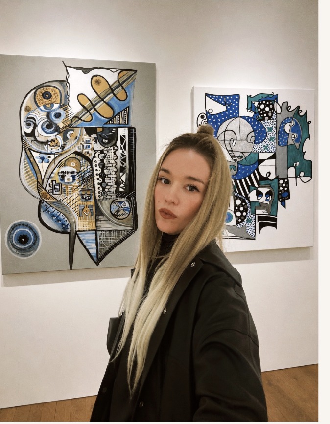 Aneta Kernová in a gallery beside two of her paintings